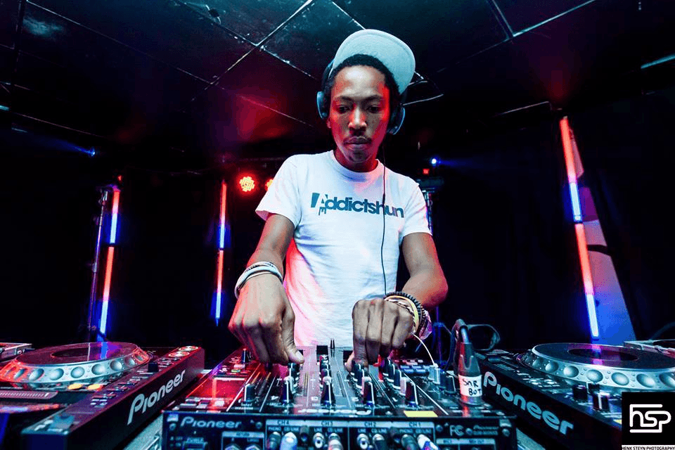 The DJ mixing in a dark club lit with red and blue light.